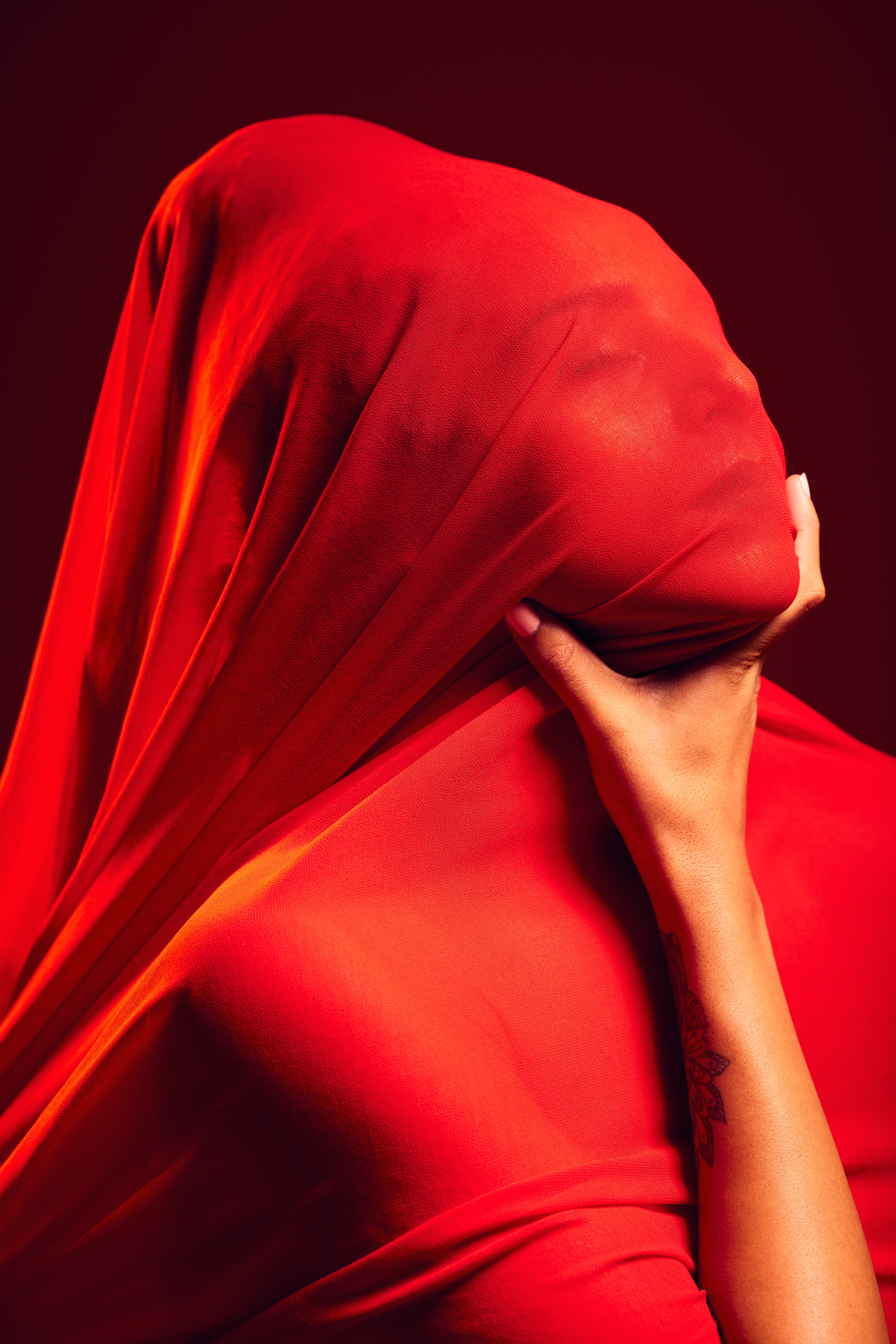 A red fabric-covered person symbolizing red flags is gripped by a hand, representing addiction, in a metaphorical representation of the blog's theme on understanding addiction patterns.