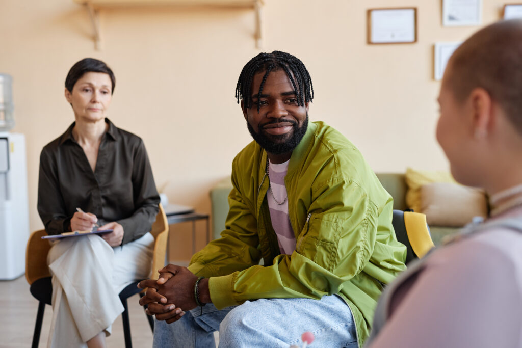 Image of a therapy session, featuring a receptive man listening attentively as another person shares their experiences, symbolizing the supportive nature of therapy in addiction treatment.
