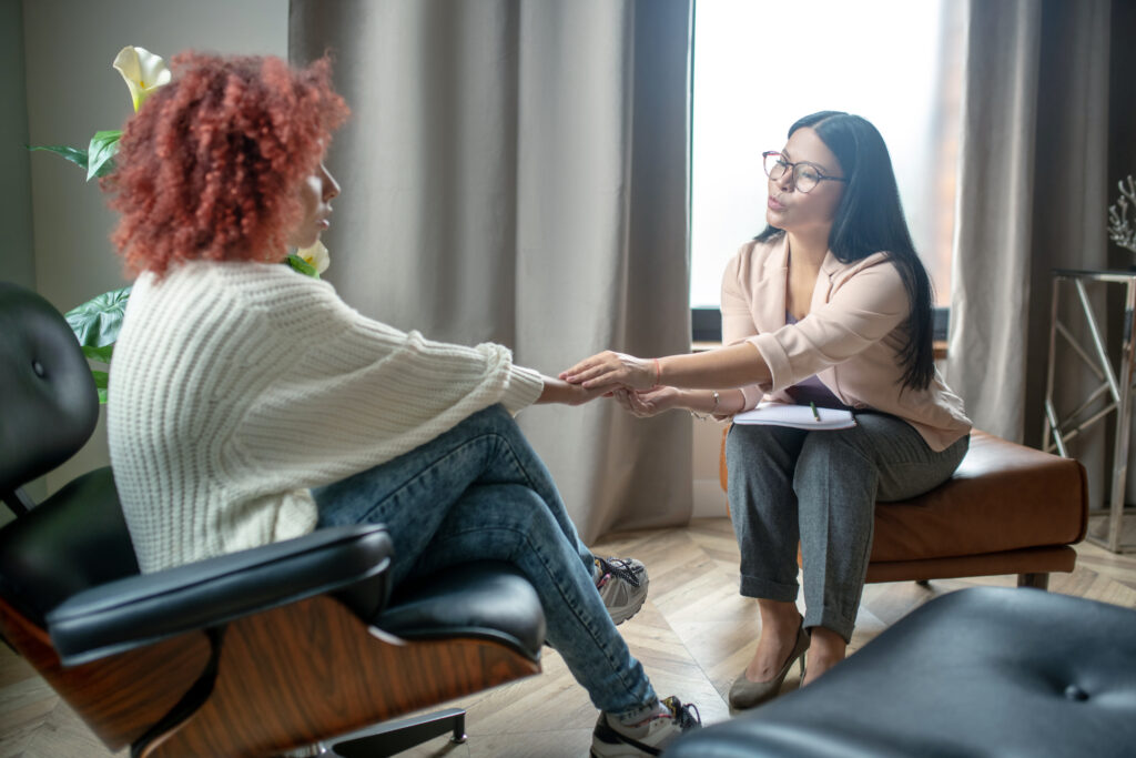 Image of a person in a therapist's office, engaged in conversation with a mental health professional. The atmosphere is calm and supportive, illustrating the transformative journey of seeking professional help to address mental health and addiction challenges amidst social stigma.