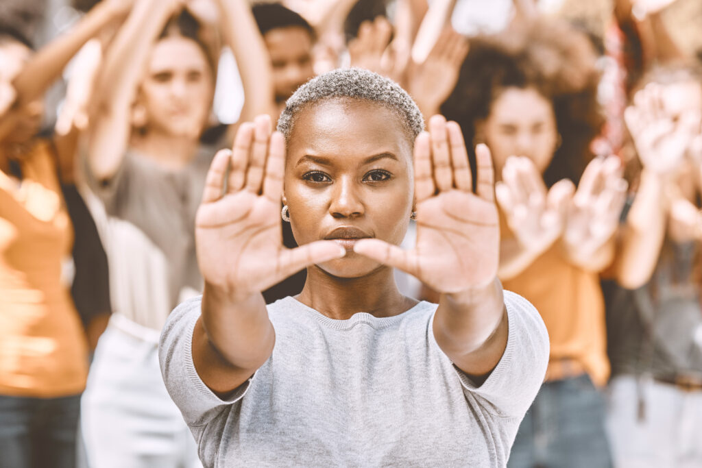Image of a woman standing in a group with outstretched hands, representing community empowerment and education initiatives for prevention.
