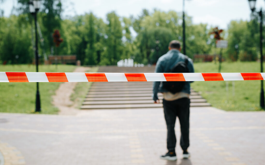 Image showing a man standing behind barrier tape, representing the social stigma and barriers to treatment in addiction.