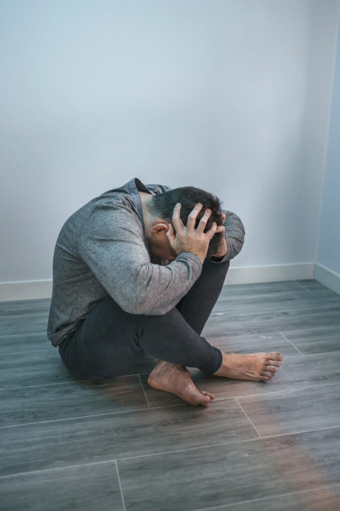 A poignant image featuring a distressed man sitting on the floor, symbolizing the theme of the blog post 'Mental Health and Addiction: Unveiling the Myths and Debunking Misconceptions.' The visual emphasizes the urgency of understanding and dismantling misconceptions related to mental health challenges.