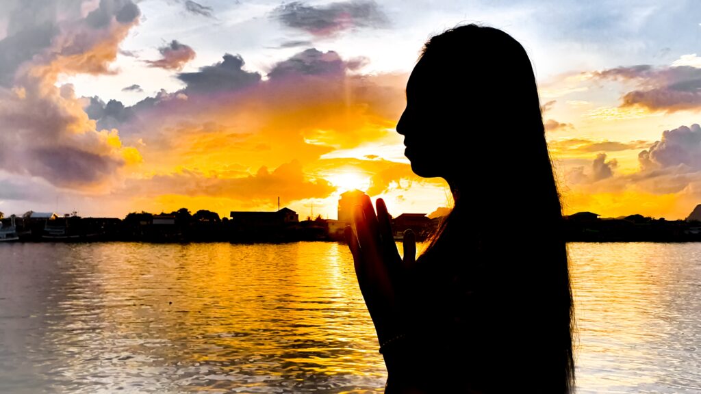 Woman in prayer position reflecting spirituality's role in mental health and addiction recovery.