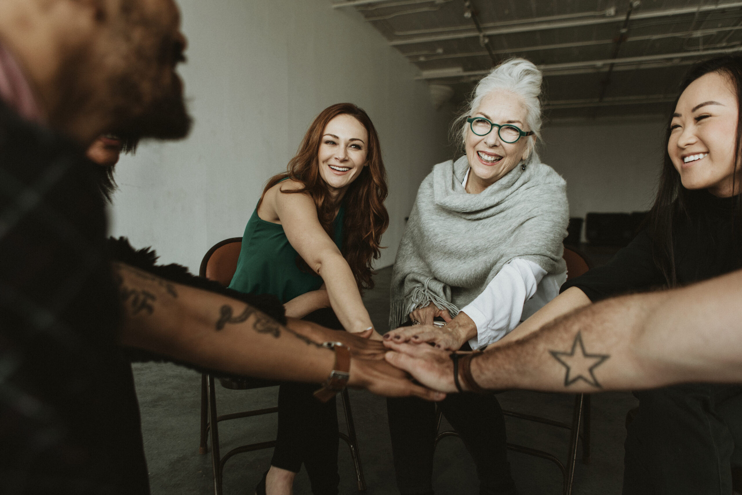 A group of happy people in a therapy circle, hands clasped together, smiling, symbolizing meaningful recovery and rediscovering purpose and passion
