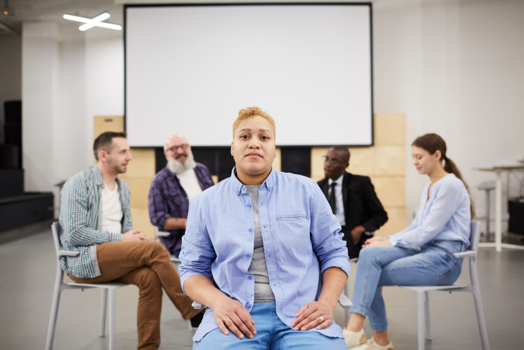  A diverse group of individuals participate in a therapy session, sitting in a circle and discussing mental health and addiction challenges, fostering a supportive environment for healing.