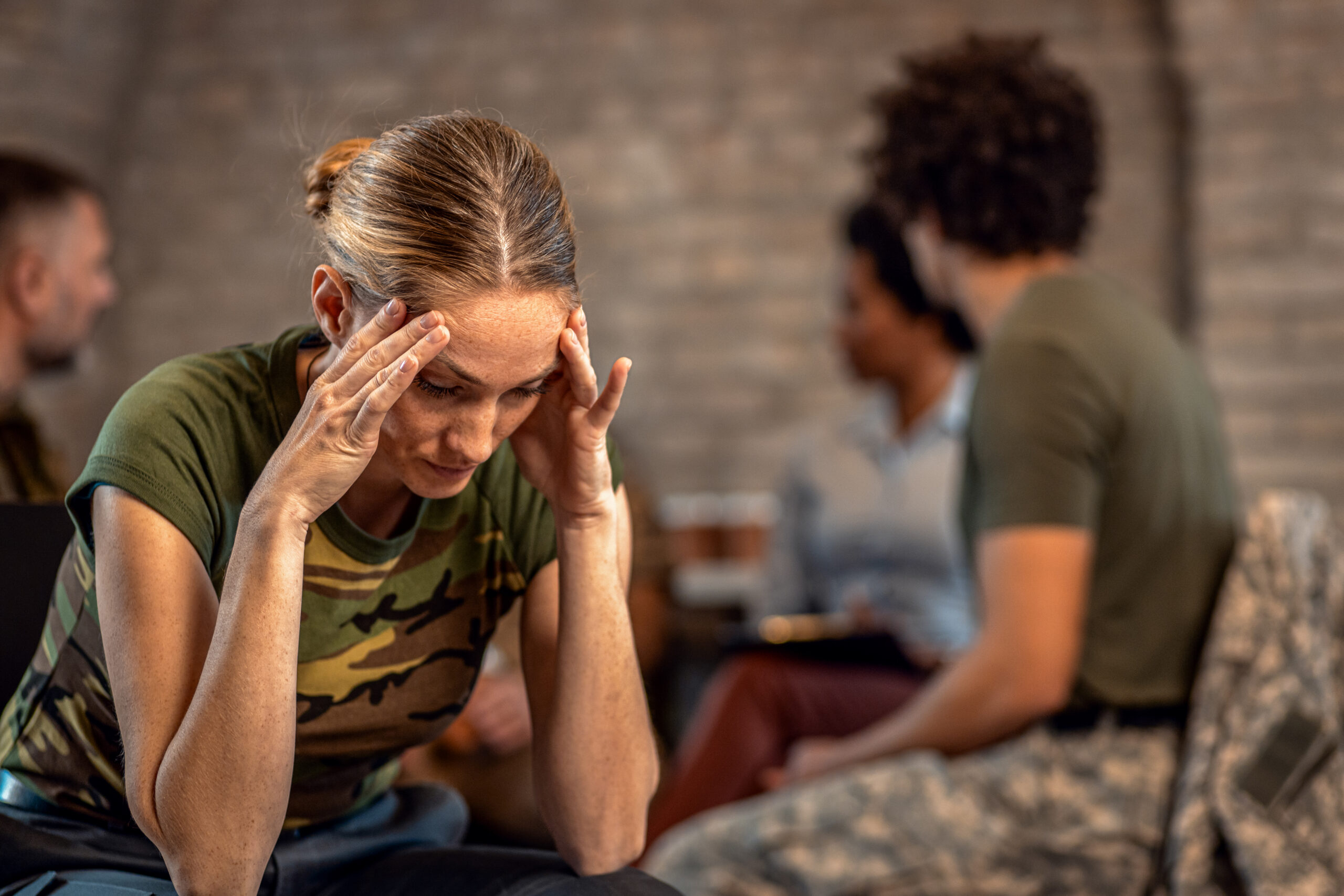 A first responder with her head in her hands sits in a therapy group, visibly distressed, as she copes with alcohol-related challenges.
