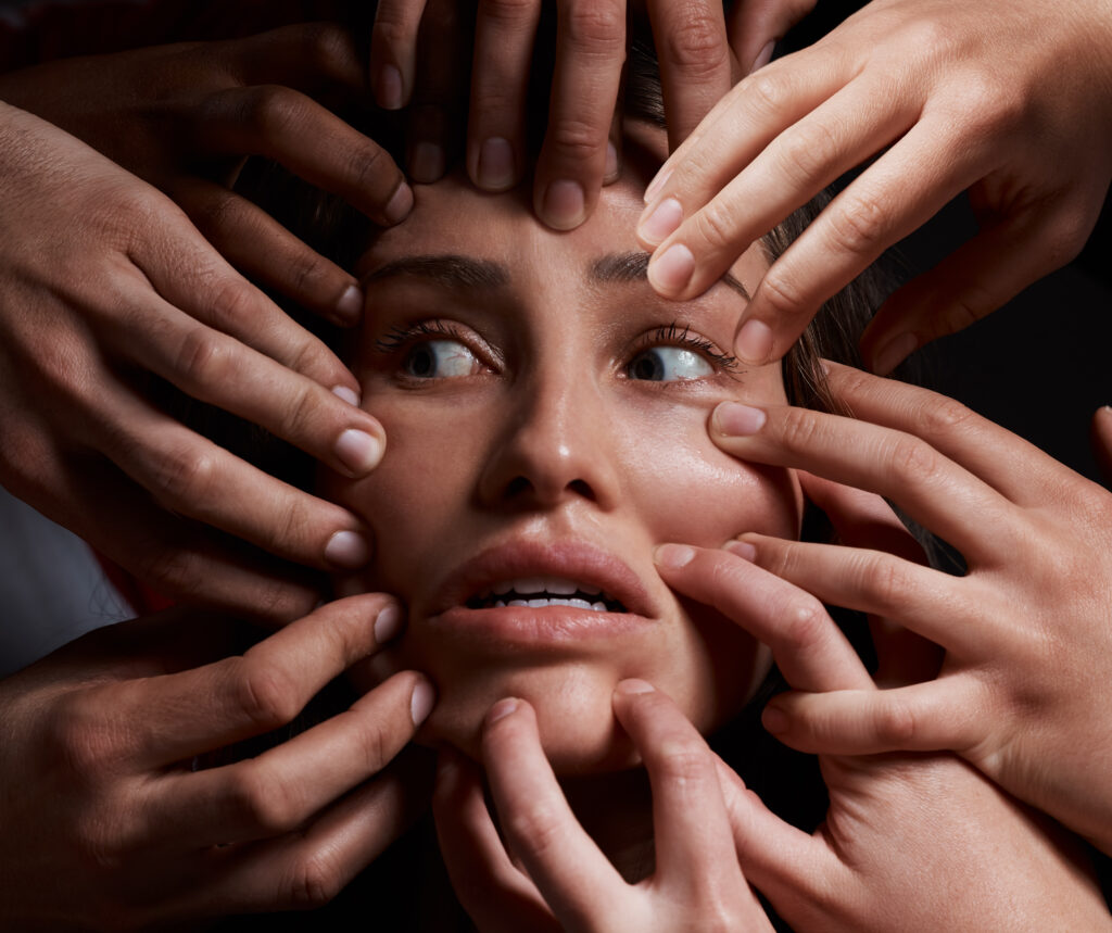 A woman's face surrounded by different hands, representing the pressures and influences on women's mental health issues in 2024.