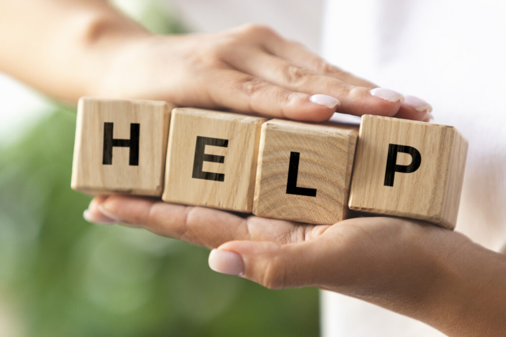 A woman holding blocks between her hands that spell out "HELP," symbolizing the importance of self-help and support strategies for mental health.