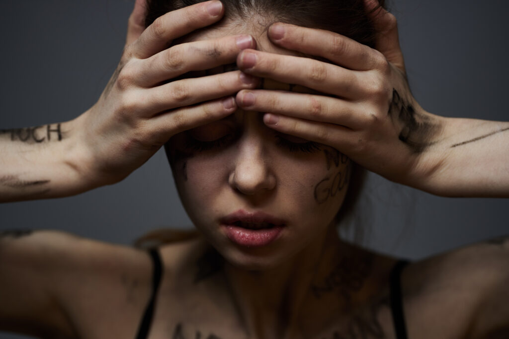 A woman with her hands on her head and eyes closed, illustrating the emotional strain of common types of mental health disorders.