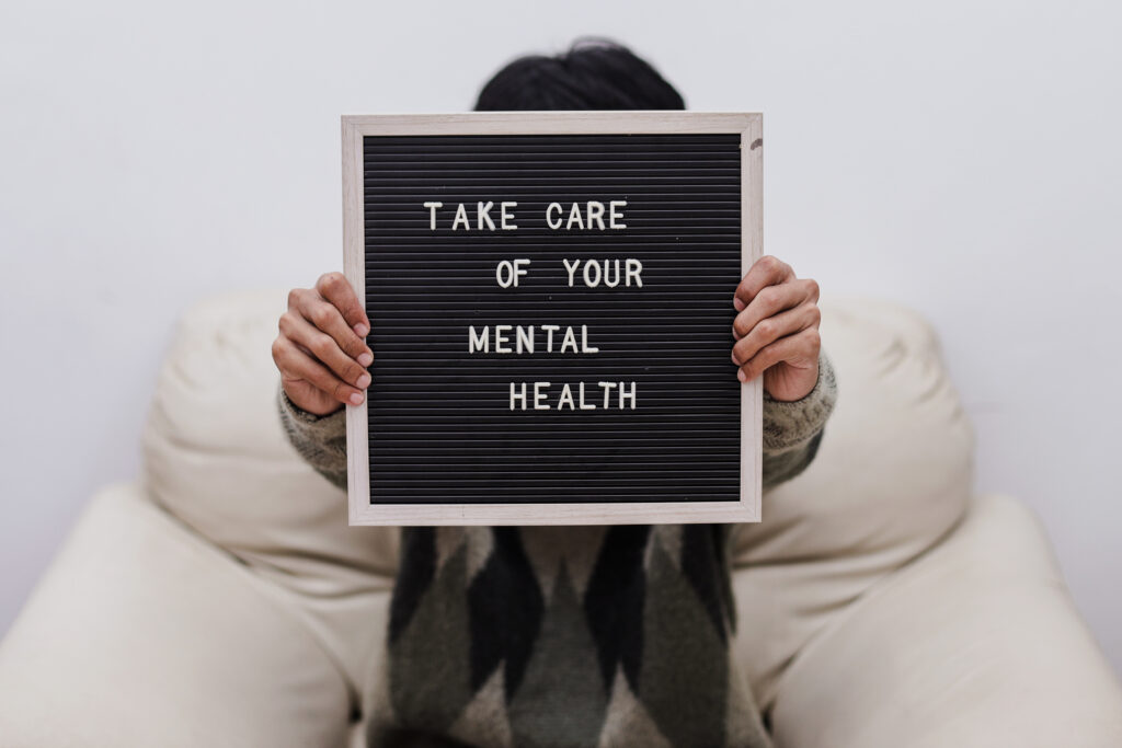 Person holding a sign that reads "Take care of your mental health," emphasizing the importance of mental health care as discussed in the mental health treatment guide.