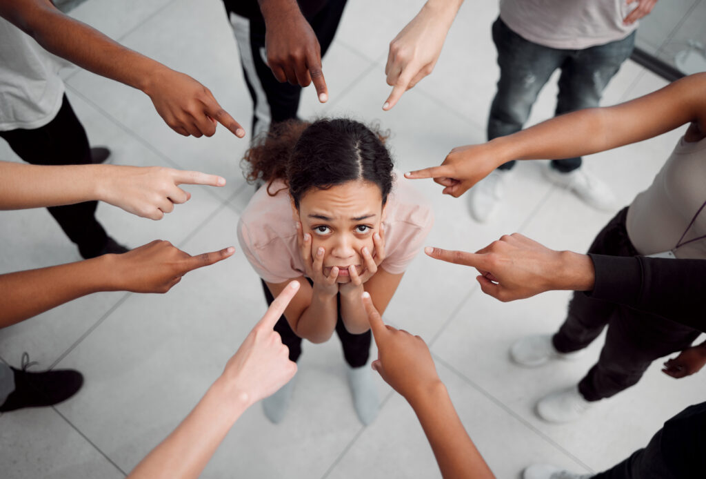 A person stands in the middle of a circle of hands pointing at them, symbolizing the stigma surrounding mental health disorders and the importance of seeking help.