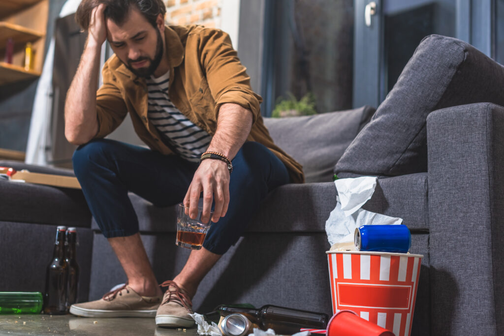 A man suffering from a hangover due to a drinking problem, highlighting the physical effects of substance abuse.