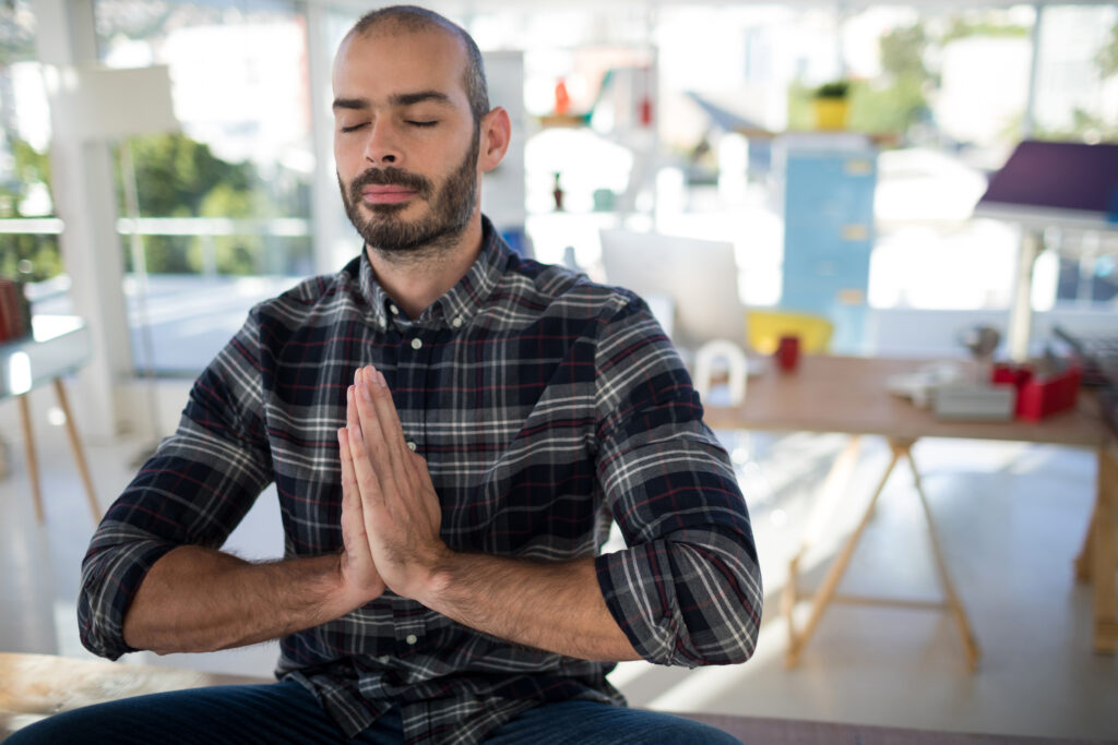 Man sitting cross-legged meditating, practicing mindfulness as a daily strategy for adults with ADHD to manage stress and anxiety.