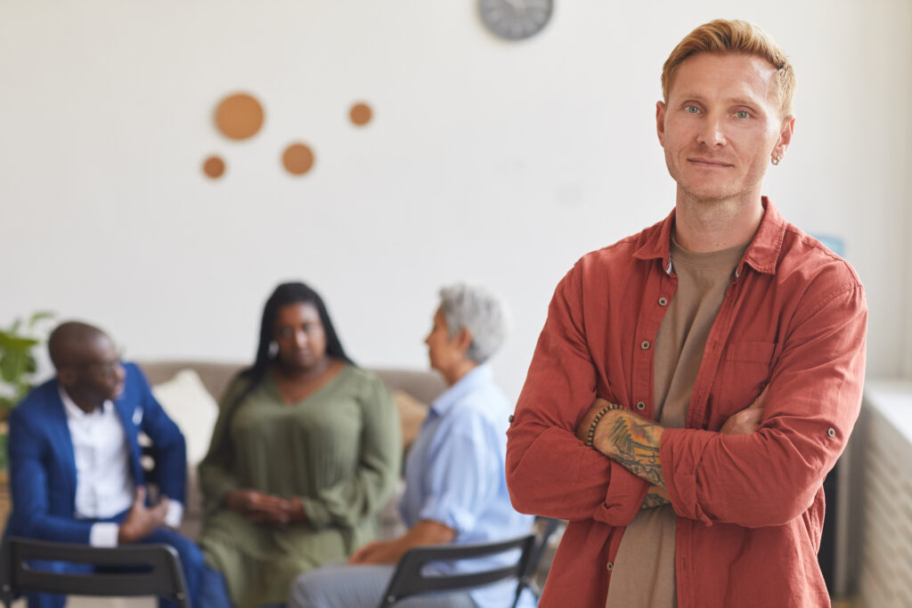 Close-up of a man with a support group in the background, representing daily strategies for adults with ADHD in managing their symptoms.