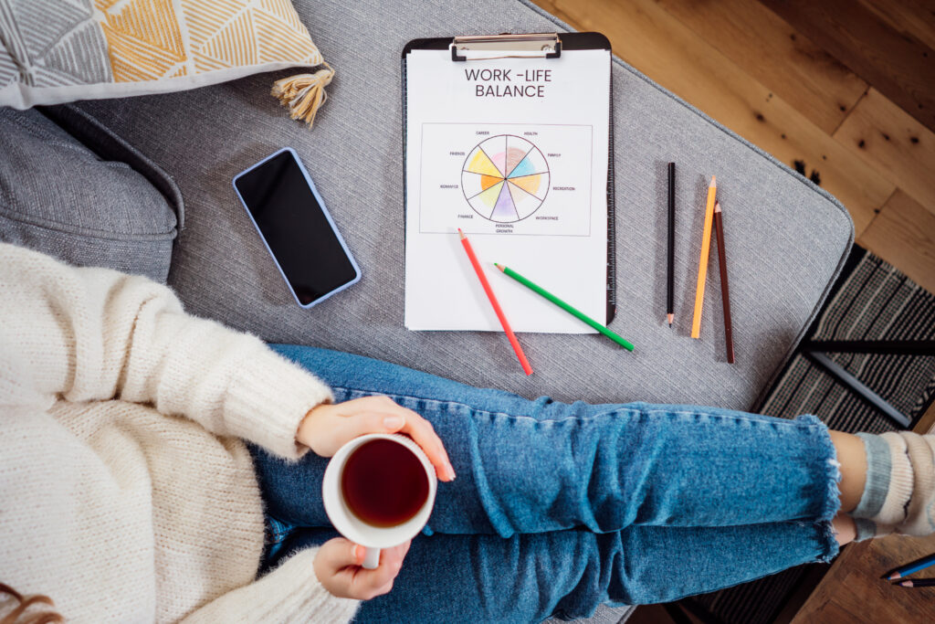 Woman sitting on a couch holding a planner titled 'Work-Life Balance,' representing daily strategies for adults with ADHD to build effective routines.