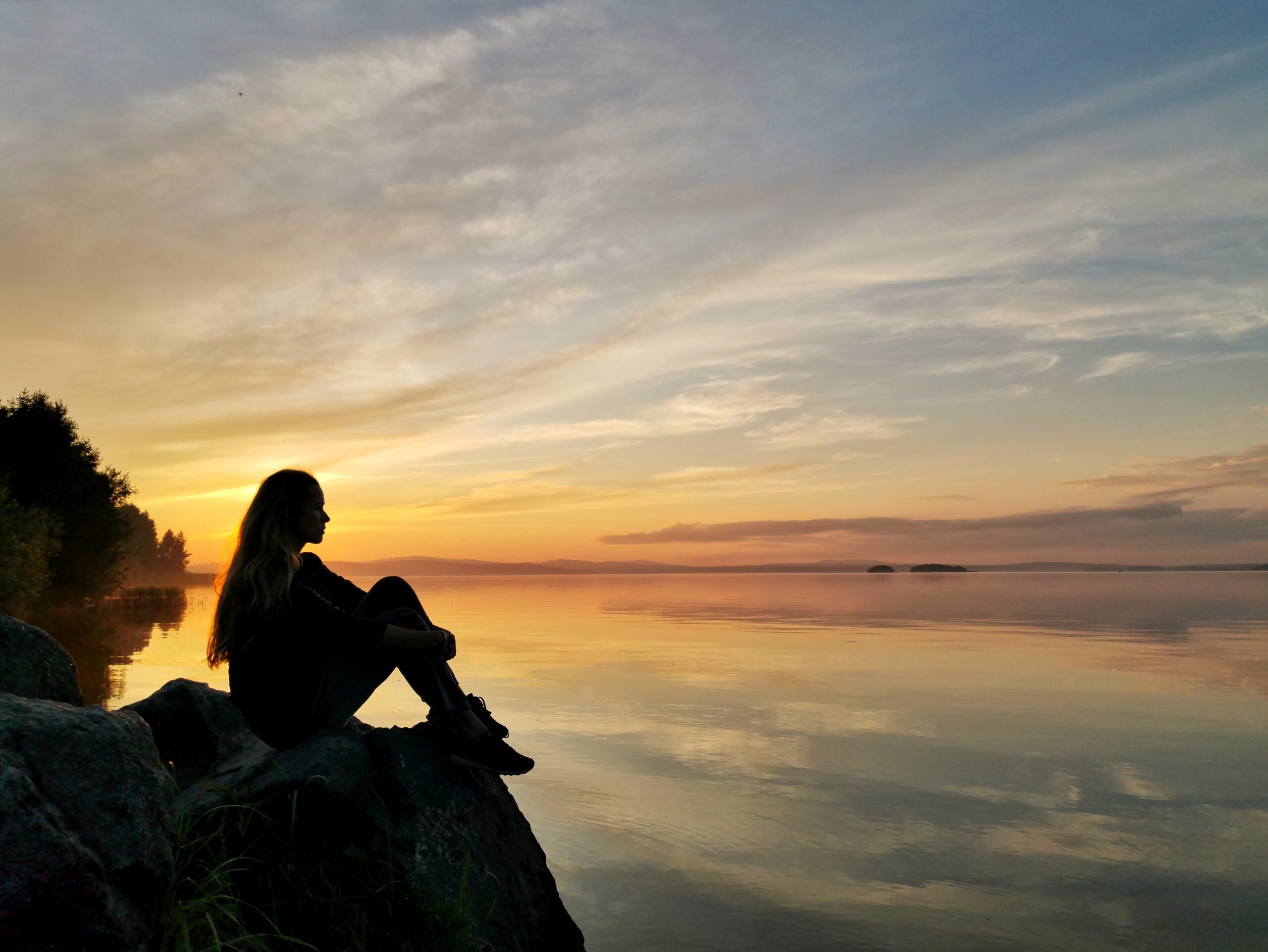 A person sitting alone in a peaceful outdoor setting, reflecting on their emotions and inner thoughts.