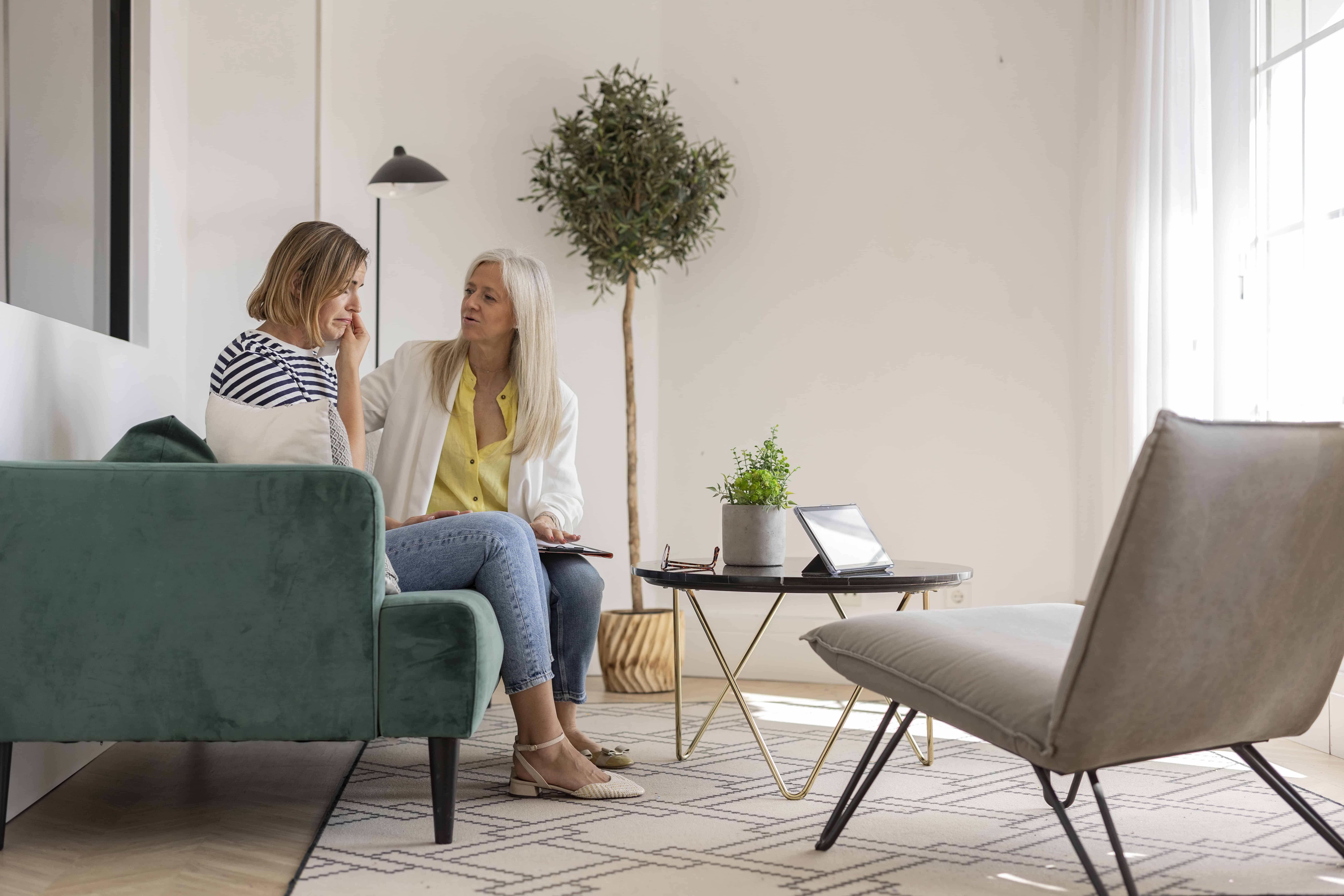 A counselor offers compassionate support to a woman during a therapy session.